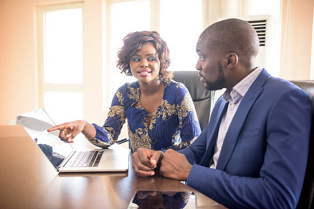 Nigerian businesswoman and male colleague at work with laptop. Businessman and woman in business meeting with computer, Nigeria, Africa.